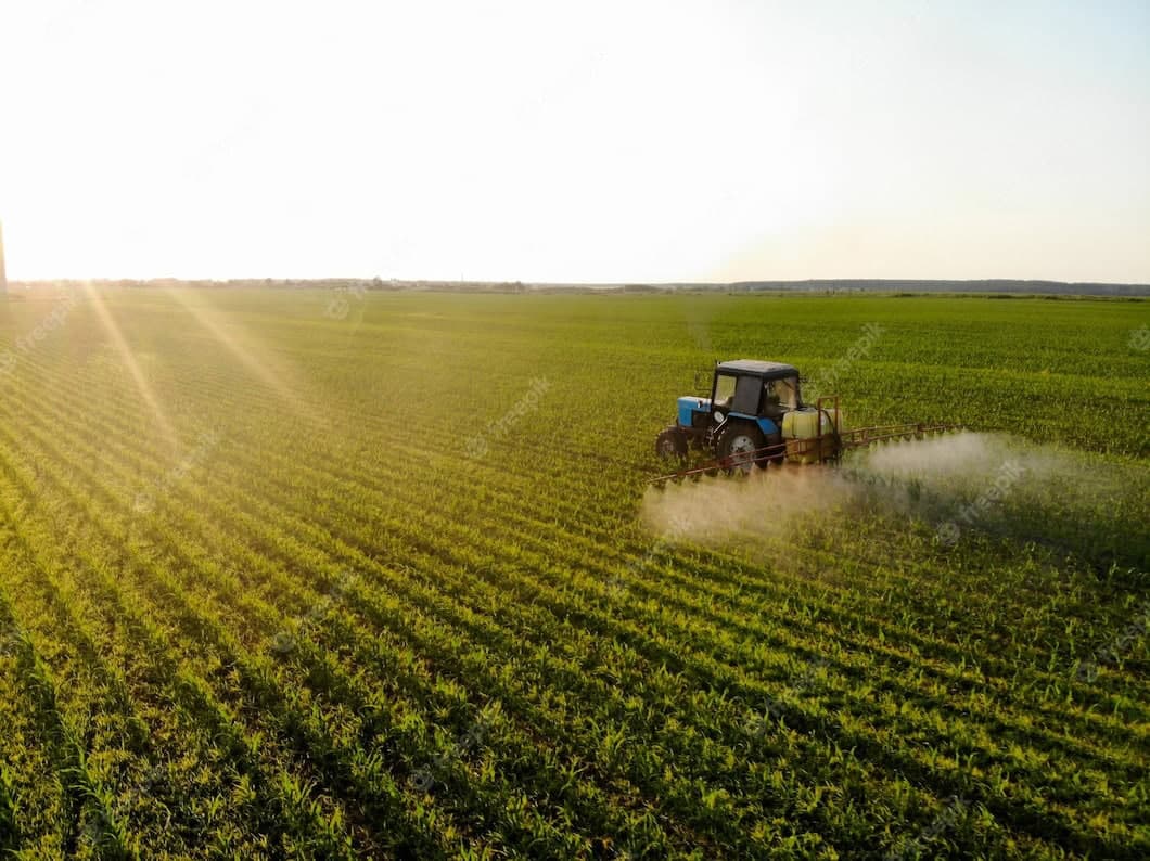 Traktor beim Besprühen von Pflanzen auf einem grünen Feld