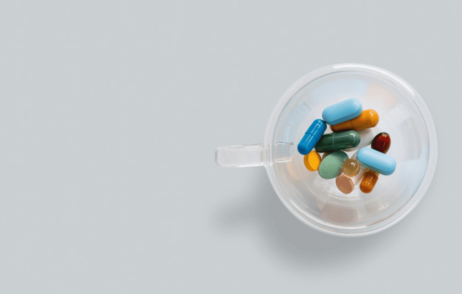 Bunte Tabletten und Kapseln in einem transparenten Becher